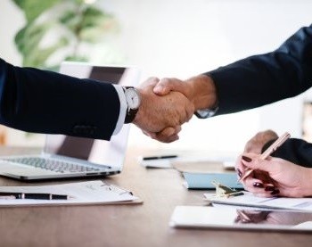 two business people shaking hands over a table.